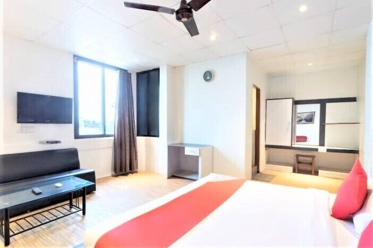 A hotel room with a bed, a desk, a chair, a TV, and a window.