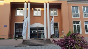 Un edificio con un ingresso centrale, ampie colonne e bandiere.