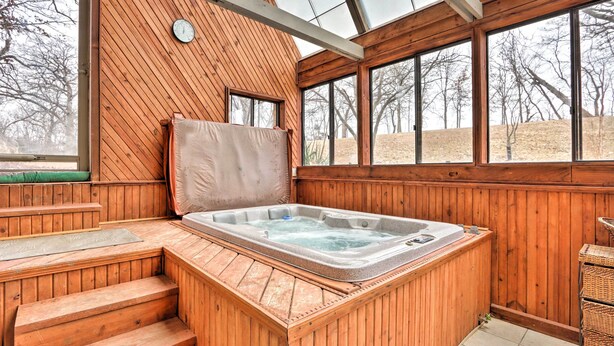 Un espacio de spa de madera con un jacuzzi, escalones de madera y ventanas amplias.