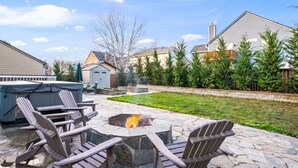 Une terrasse extérieure avec des fauteuils Adirondack, un foyer en pierre et un jacuzzi.
