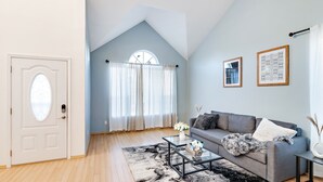 Un salon moderne avec un canapé gris, une table basse en verre et un tapis noir et blanc.