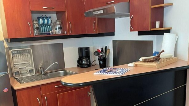 A compact kitchen with wooden cabinets, a stainless steel sink, and a black countertop. - Mobile home for 6 people. (Arvert)