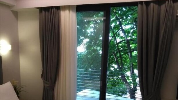 A modern hotel room with a large bed, a view of the outdoors through a sliding glass door, and a small side table with a lamp. - Konak Bella 3 (Istanbul)