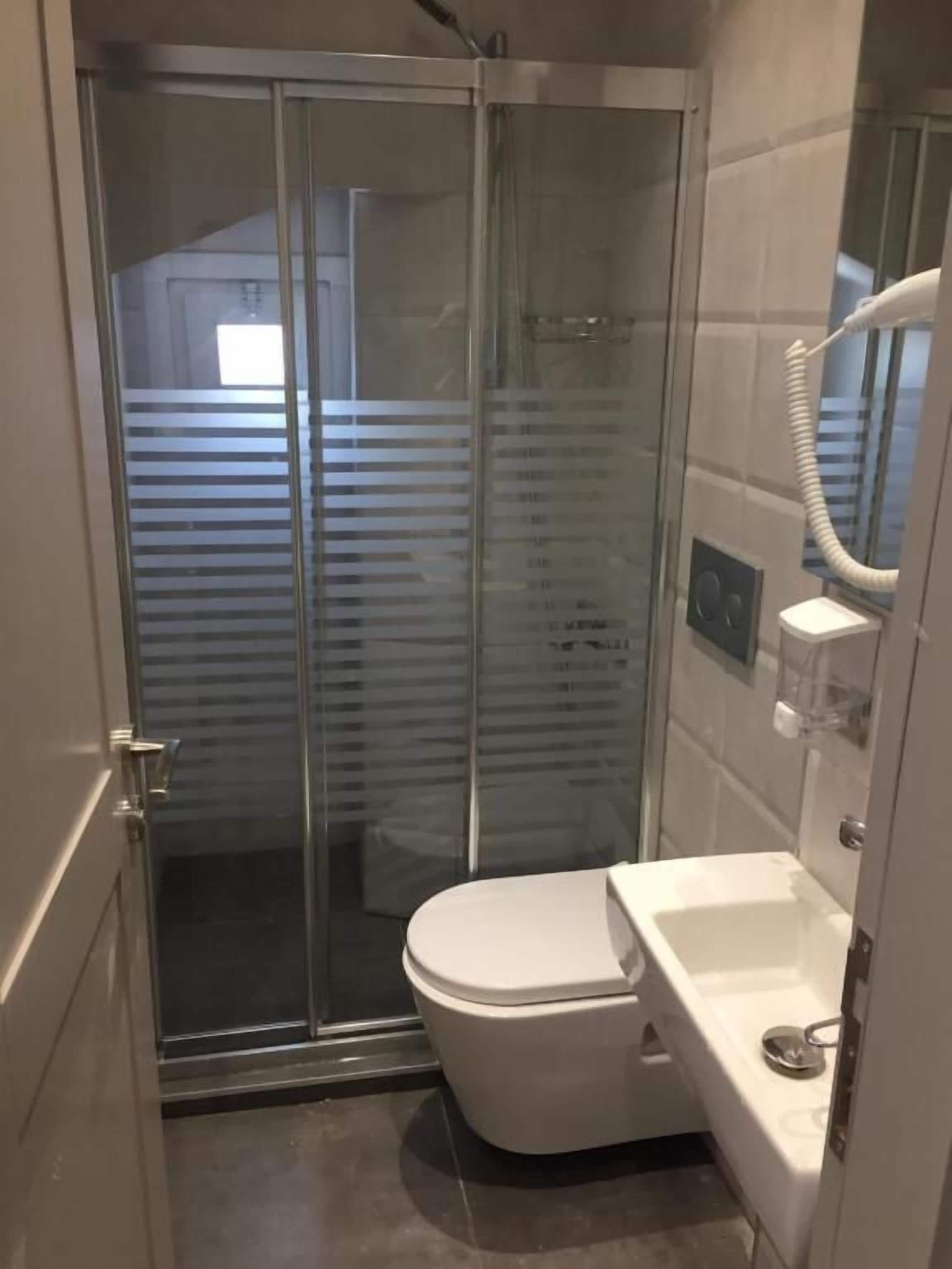 Ein modernes Badezimmer mit einer Duschkabine, einer weißen Toilette und einem Waschbecken mit Spiegel.