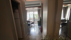 A hallway with a tiled floor leading to a dining area with a table and chairs. There is a plant in the foreground. - Konak Bella 3 (Istanbul)