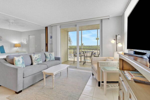 A modern living room with a grey sofa, a small white coffee table, and a TV on a wooden stand.