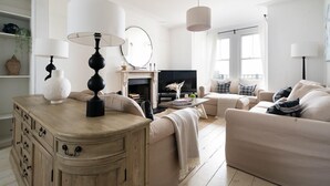 Een moderne woonkamer met een houten kast, beige banken, een televisie en een open haard.