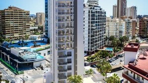 A high-rise hotel with multiple balconies, a rooftop pool, and a view of surrounding buildings.