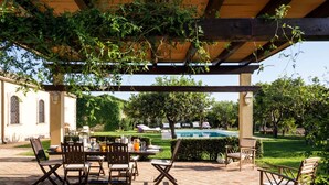Une terrasse extérieure avec une table et des chaises, une piscine et un jardin.
