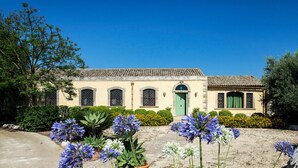 Un bâtiment à deux étages, doté d’un toit recouvert de tuiles, d’une porte verte et d’un petit balcon.