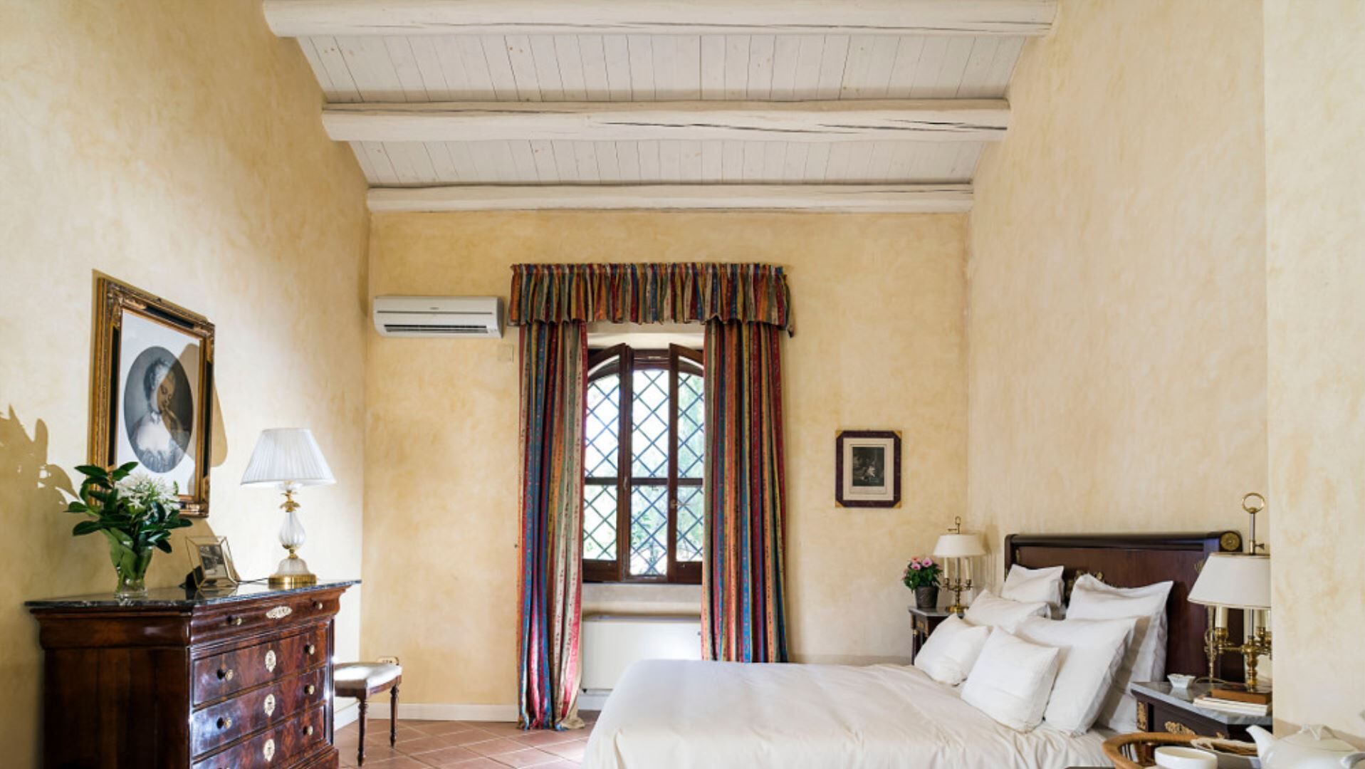 Un dormitorio con cama, cómoda y ventana con cortinas.