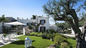 Eine moderne Villa mit gepflegtem Garten, einem weißen Sonnenschirm und einer Laterne.