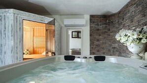 Ein Wellnessbereich mit Whirlpool, Holzwänden und einer Steinwand.