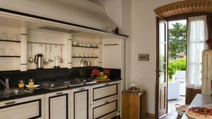 A kitchen with white cabinets, black countertops, and a wooden table with food.