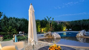 A poolside area with a covered umbrella, lounge chairs, and a bowl of fruit. - Independent villa up to 16 guests (Buseto Palizzolo)