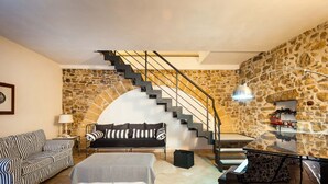 A modern living room with a stone wall, a staircase, a sofa, a piano, and a lamp. - Independent villa up to 16 guests (Buseto Palizzolo)