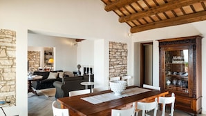 A spacious living area with a stone wall, a wooden dining table, and a traditional cabinet.
