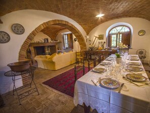 A dining area with a long table set for a meal, brick arches, and a fireplace.