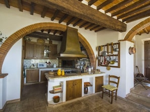 A rustic kitchen with exposed wooden beams, a central island, and a hanging pot rack.