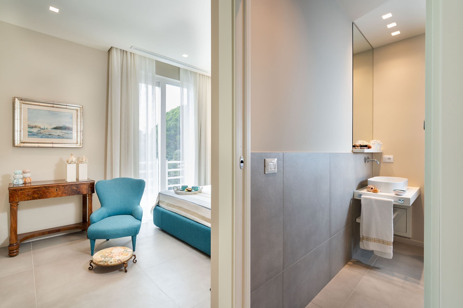 Een moderne badkamer met een grote spiegel, een witte wasbak en een handdoek aan de muur.
