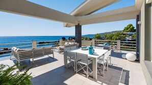 Eine Terrasse mit Meerblick, ausgestattet mit Gartenmöbeln und einem Pool.