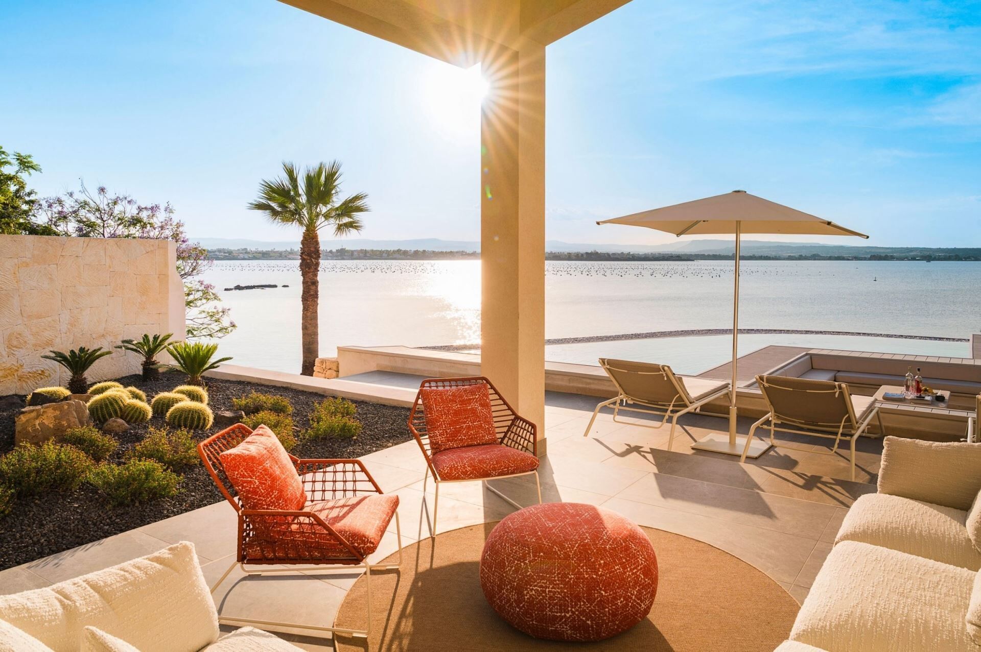 A sunlit outdoor seating area with a view of the beach and water.
