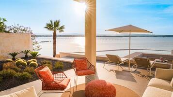 A sunlit outdoor seating area with a view of the beach and water.