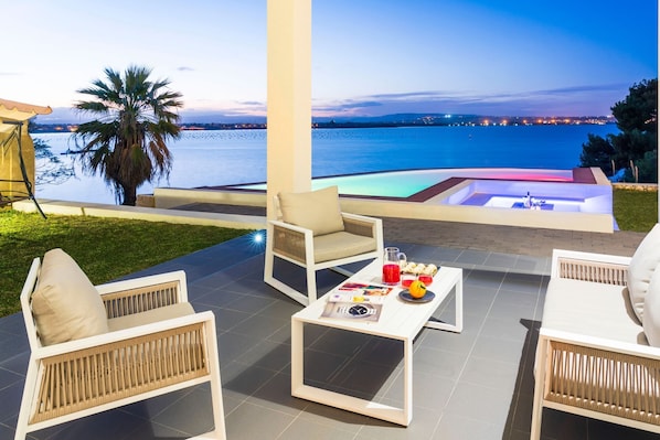A terrace with outdoor seating, a pool, and a view of the sea.