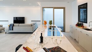 A modern kitchen with a marble countertop, a dining area with a sofa, and a large window overlooking a body of water. - Dream Villa with heated pool and magnificent view on the Taormina Bay (Letoianni)