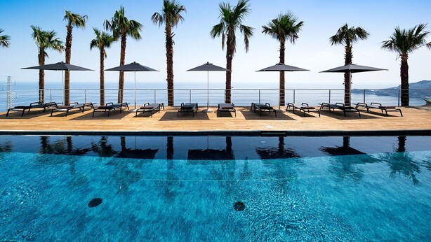 A poolside area with lounge chairs and umbrellas, overlooking a body of water. - Dream Villa with heated pool and magnificent view on the Taormina Bay (Letoianni)