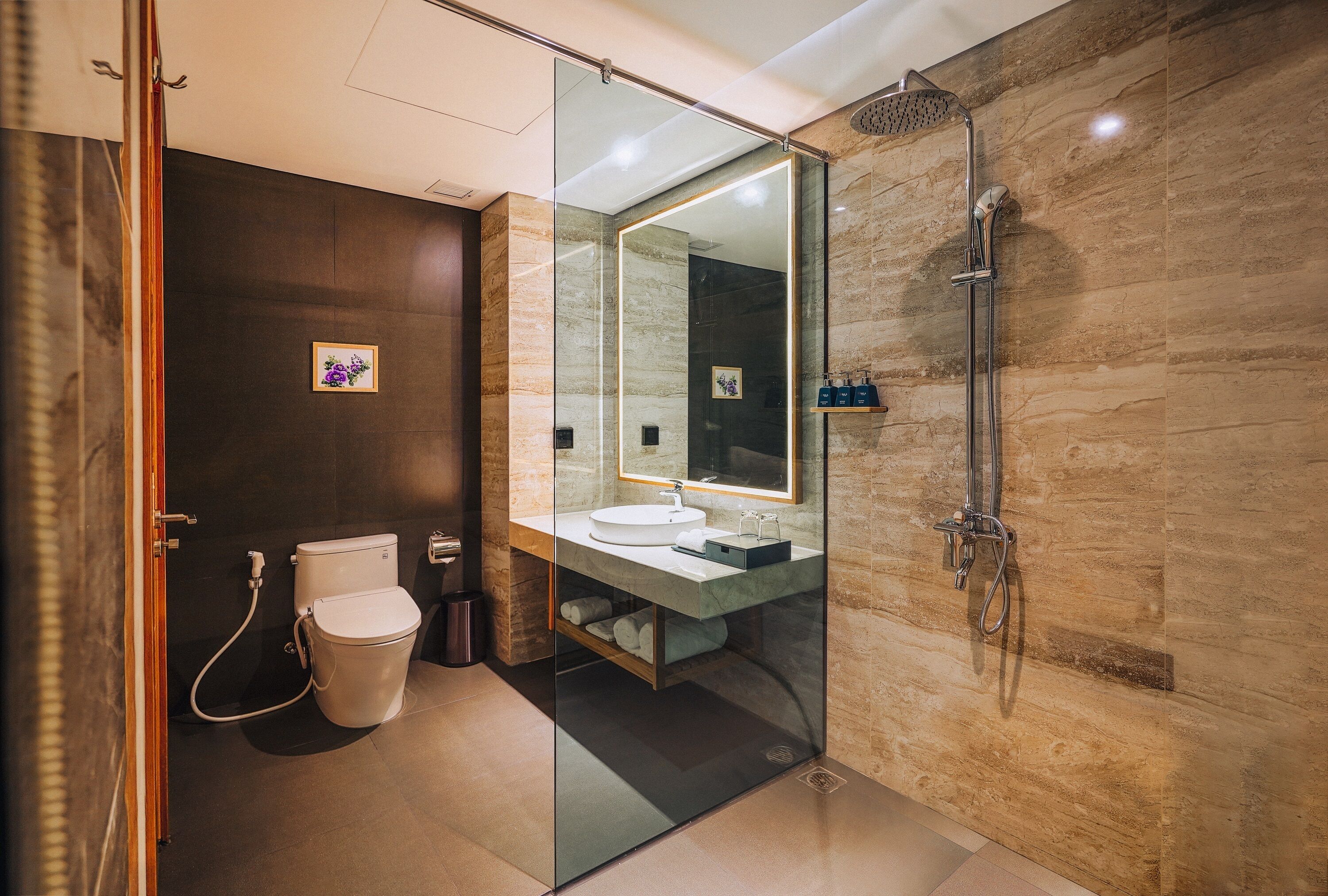 A modern bathroom with a glass-enclosed shower, a toilet, and a sink with a mirror.
