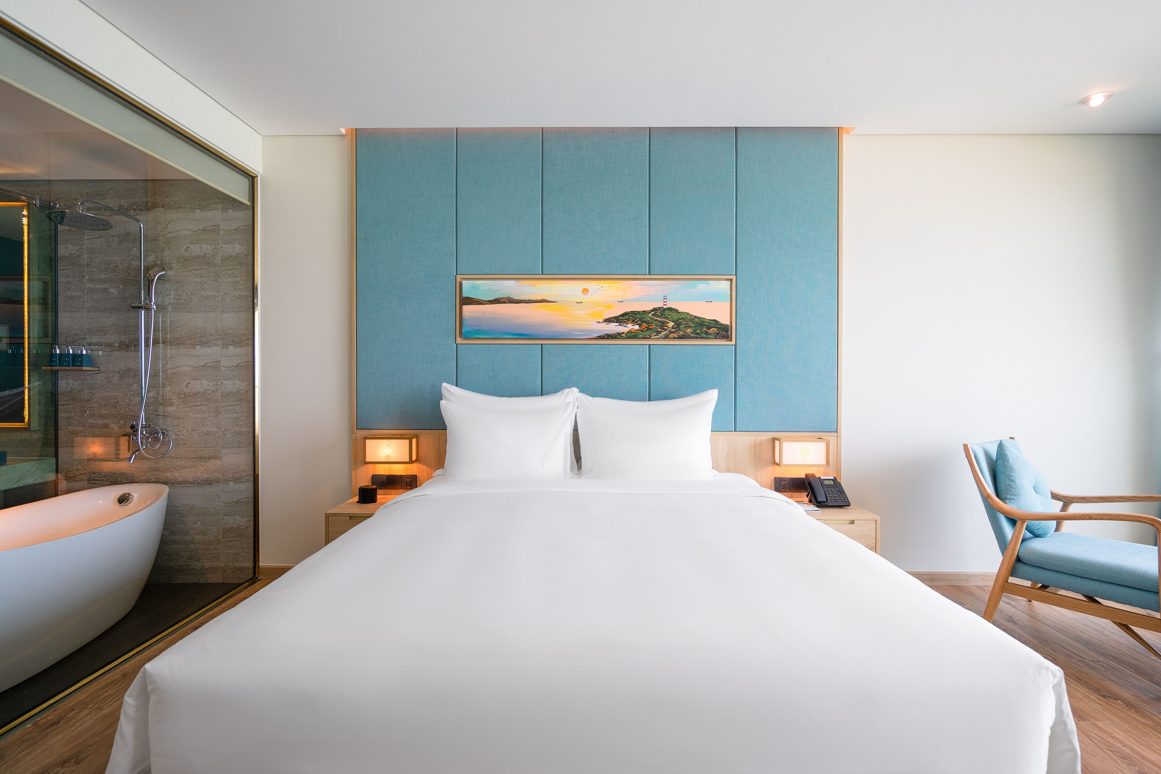 Une chambre d’hôtel moderne avec un grand lit, une baignoire, une chaise et un tableau au mur.
