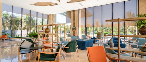 A spacious lobby with modern furniture, large windows, and a view of palm trees.