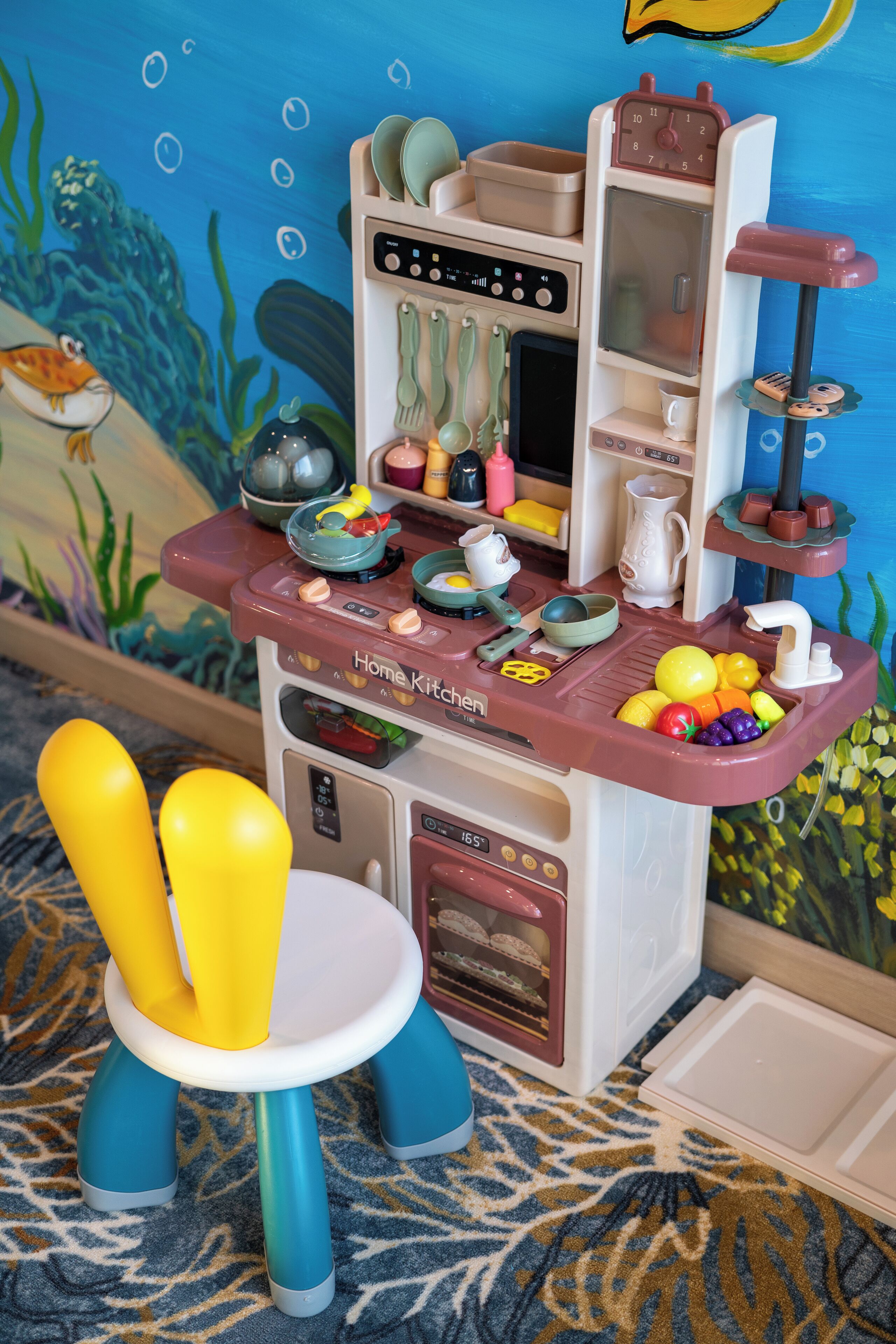 A children's play kitchen with a sink, stove, and various utensils.