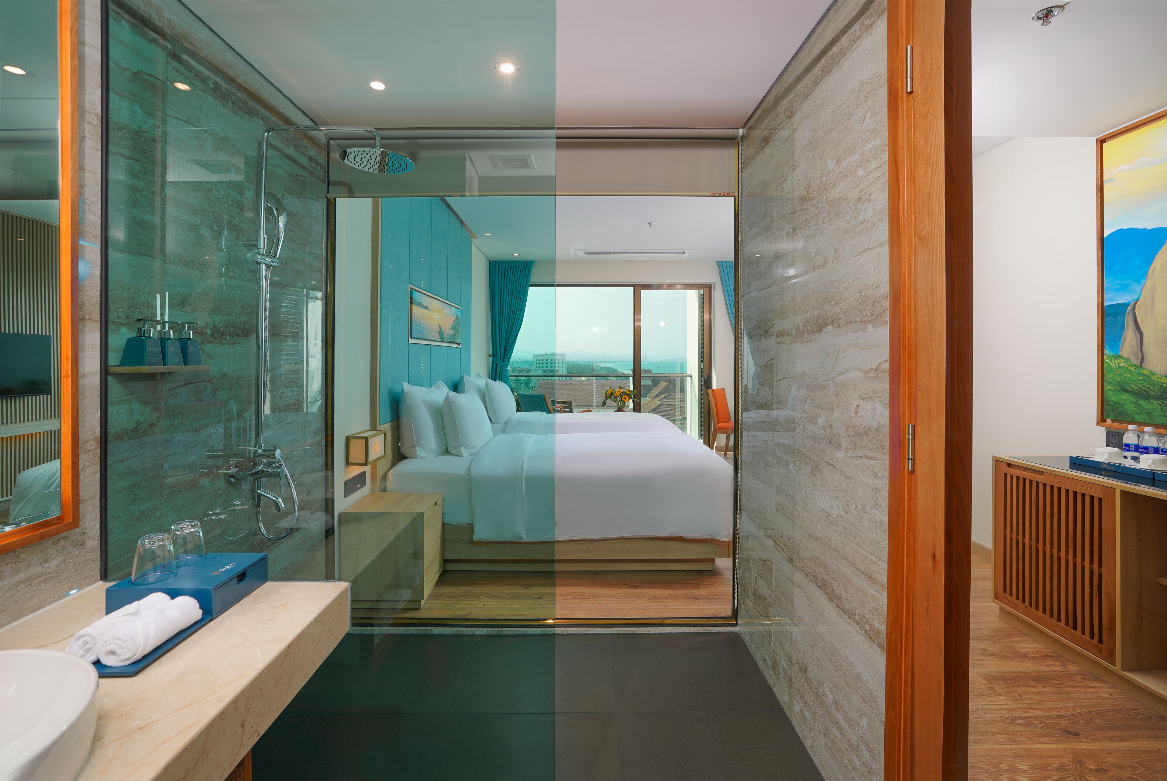 Een moderne hotelkamer met een glazen douchecabine, een groot bed, een houten kaptafel en uitzicht op de stad.