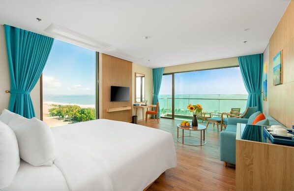 A hotel room with a large bed, a desk, a TV, and a balcony with a view of the ocean. - Sala Grand Tuy Hoa Hotel (Tuy Hoa)