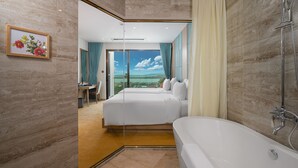 Une chambre d’hôtel moderne dotée d’un grand lit, d’une salle de bain séparée et offrant une vue panoramique à travers la porte vitrée.