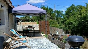 Een houten terras met een barbecue, een overdekte patio en een zwembad.