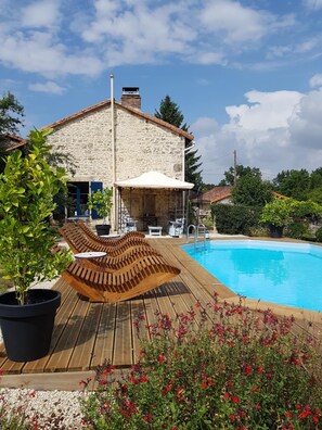 A stone house with a wooden deck and a swimming pool. - CHARMING COTTAGE WITH TERRACE OVERLOOKING THE COUNTRYSIDE (BIOUSSAC)