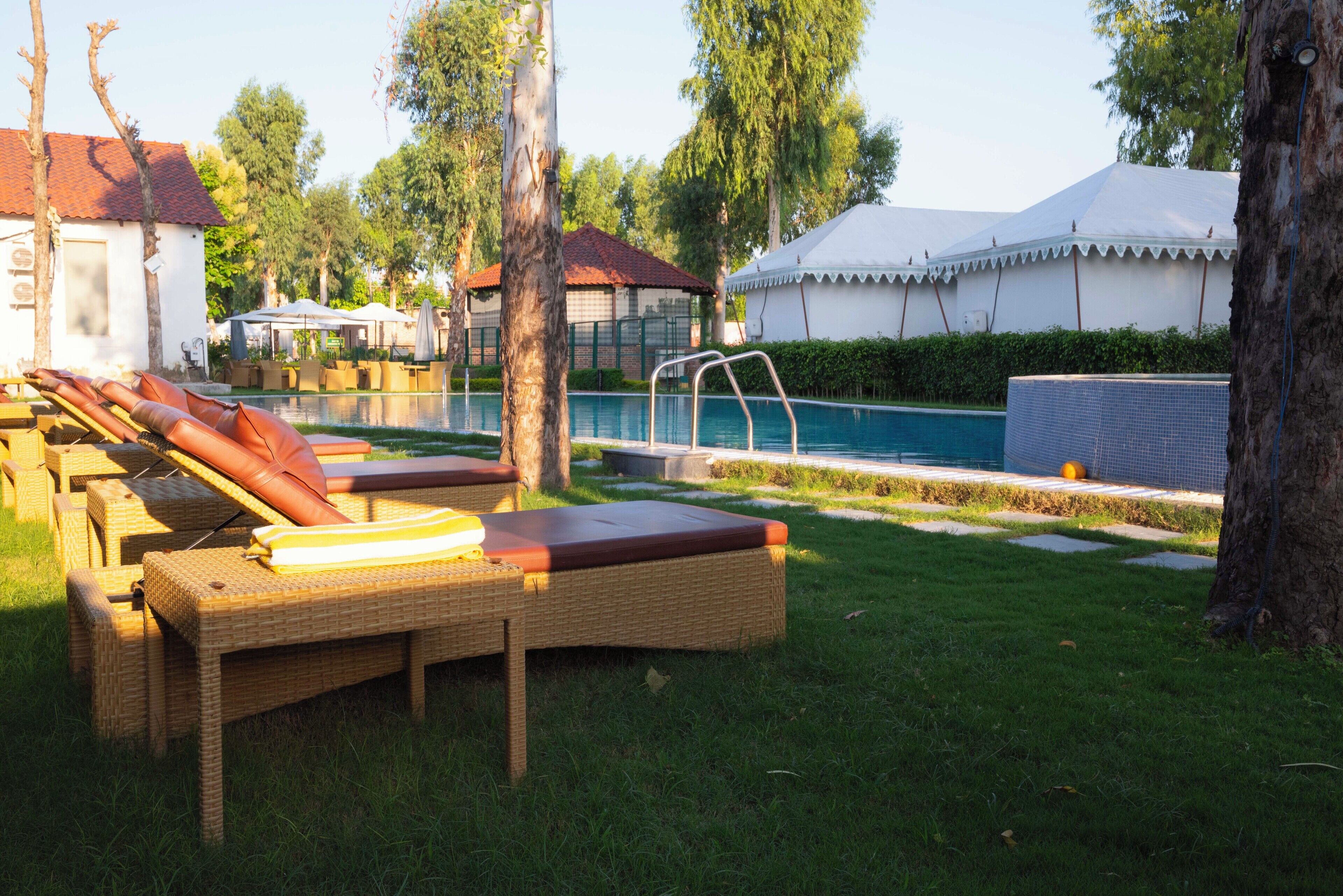 A poolside area with lounge chairs, a small pool, and a tent structure.