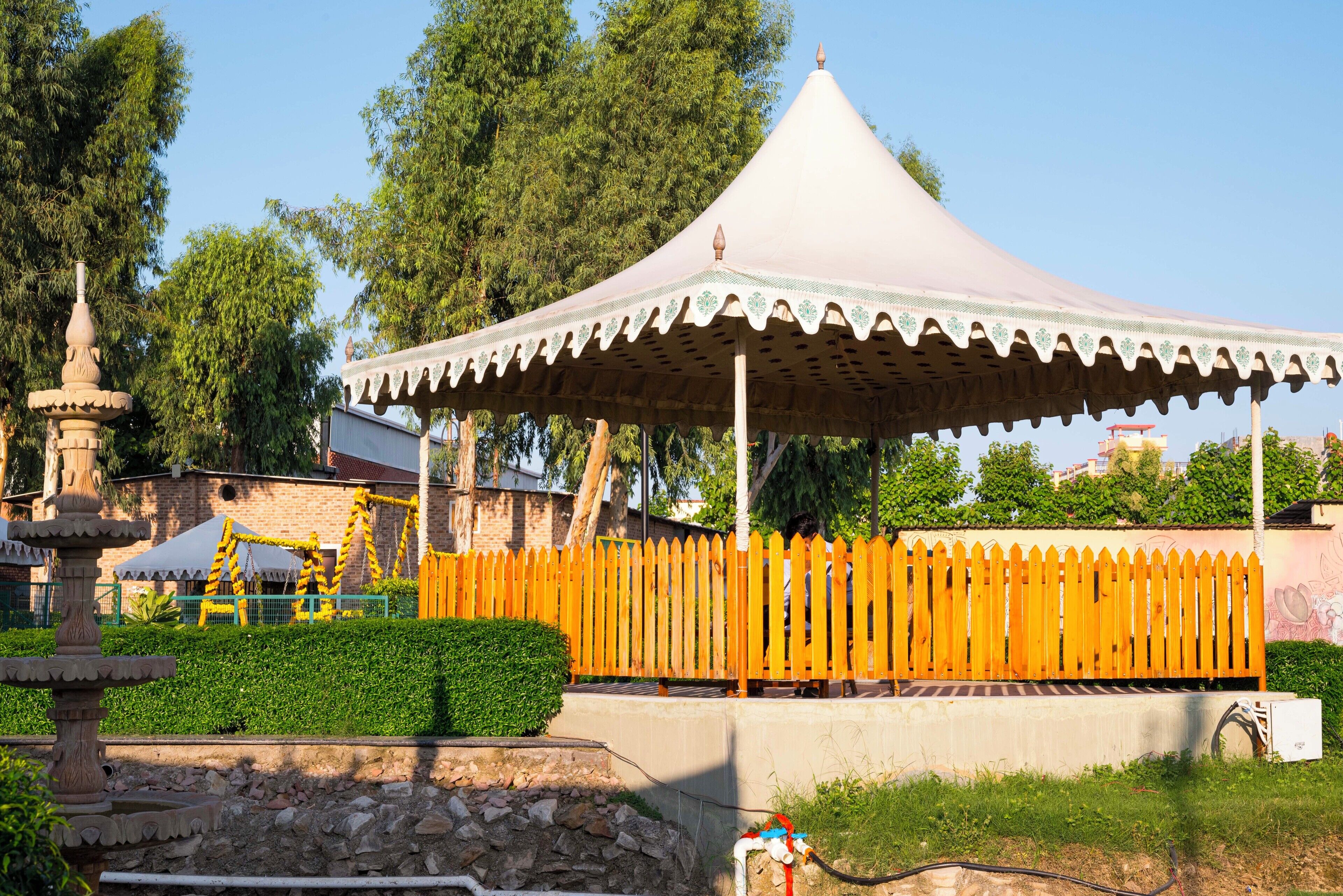 A gazebo with a conical roof and a wooden fence in a park.