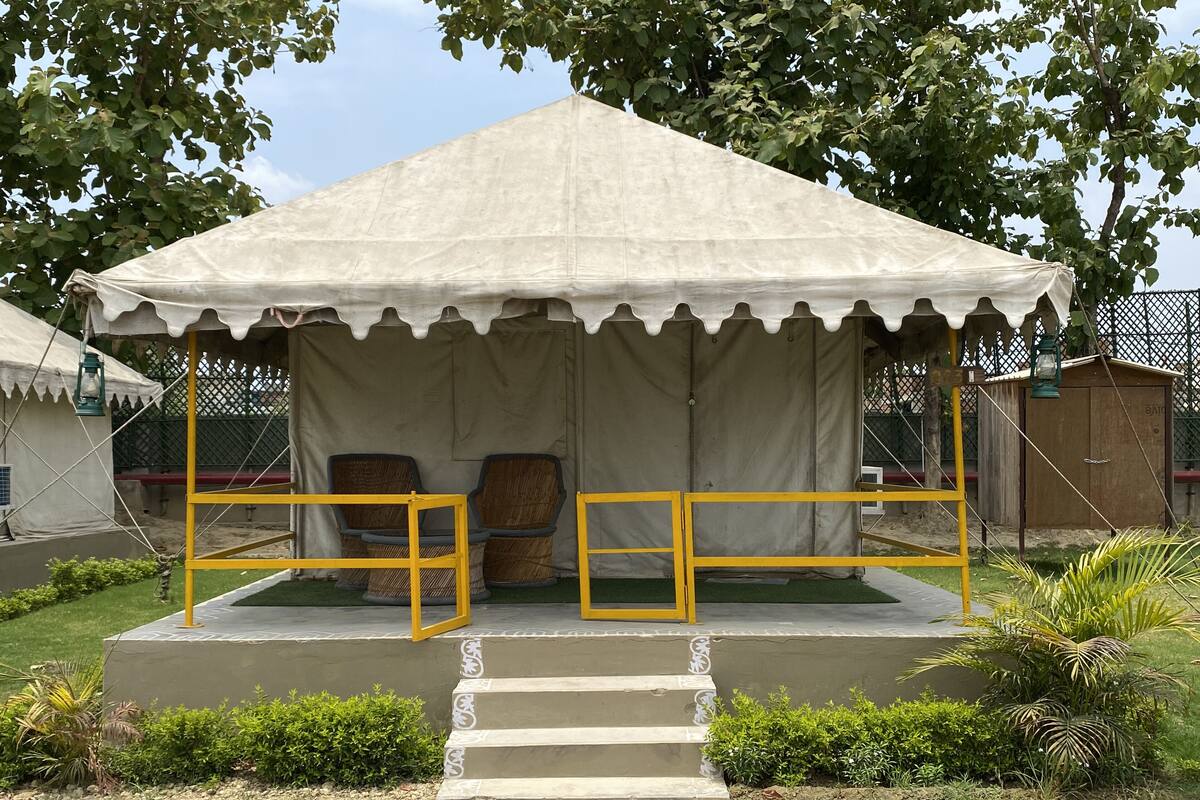 A tent with two chairs and a small platform with steps leading up to it.