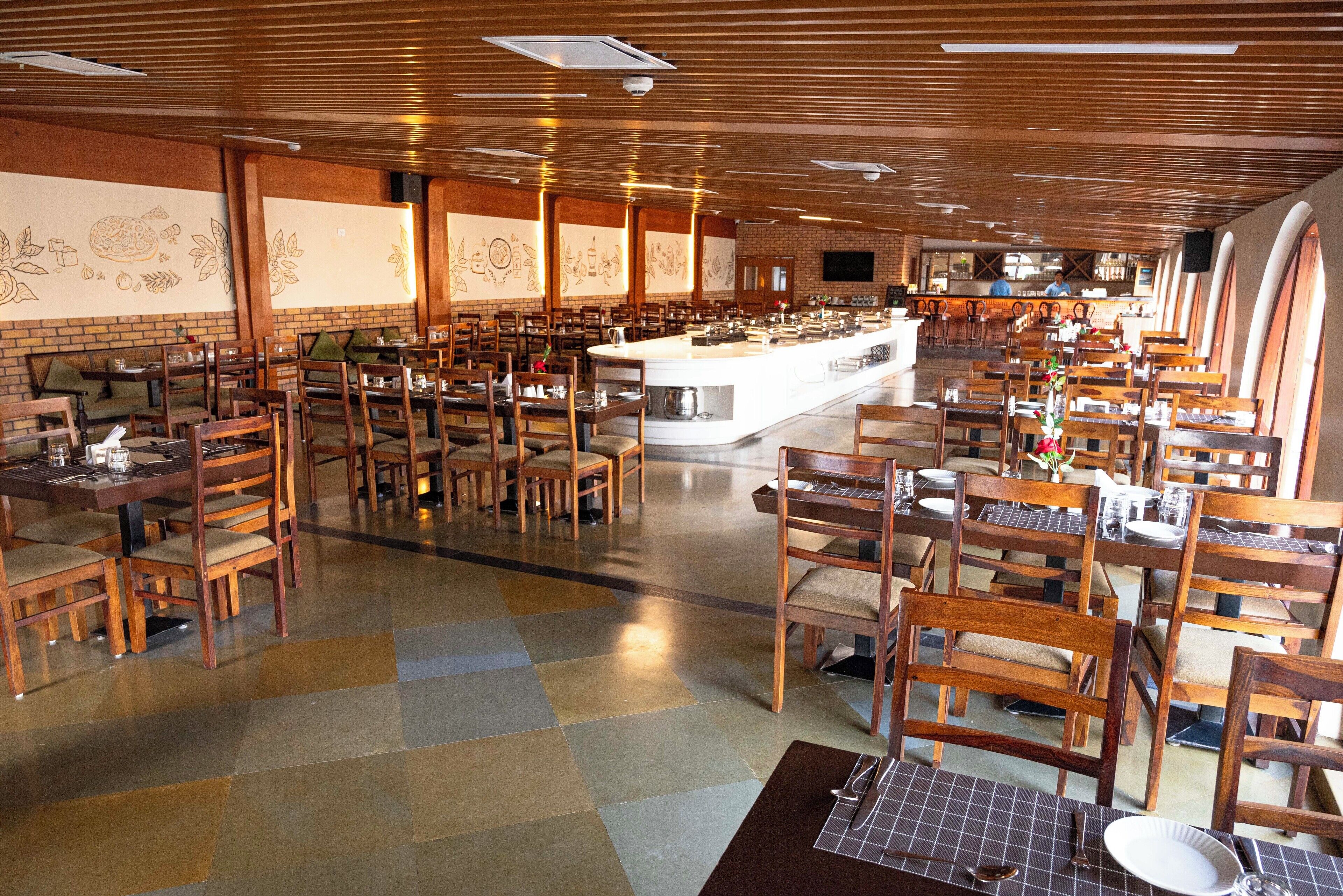 A spacious restaurant with wooden furniture, a central bar, and a tiled floor.