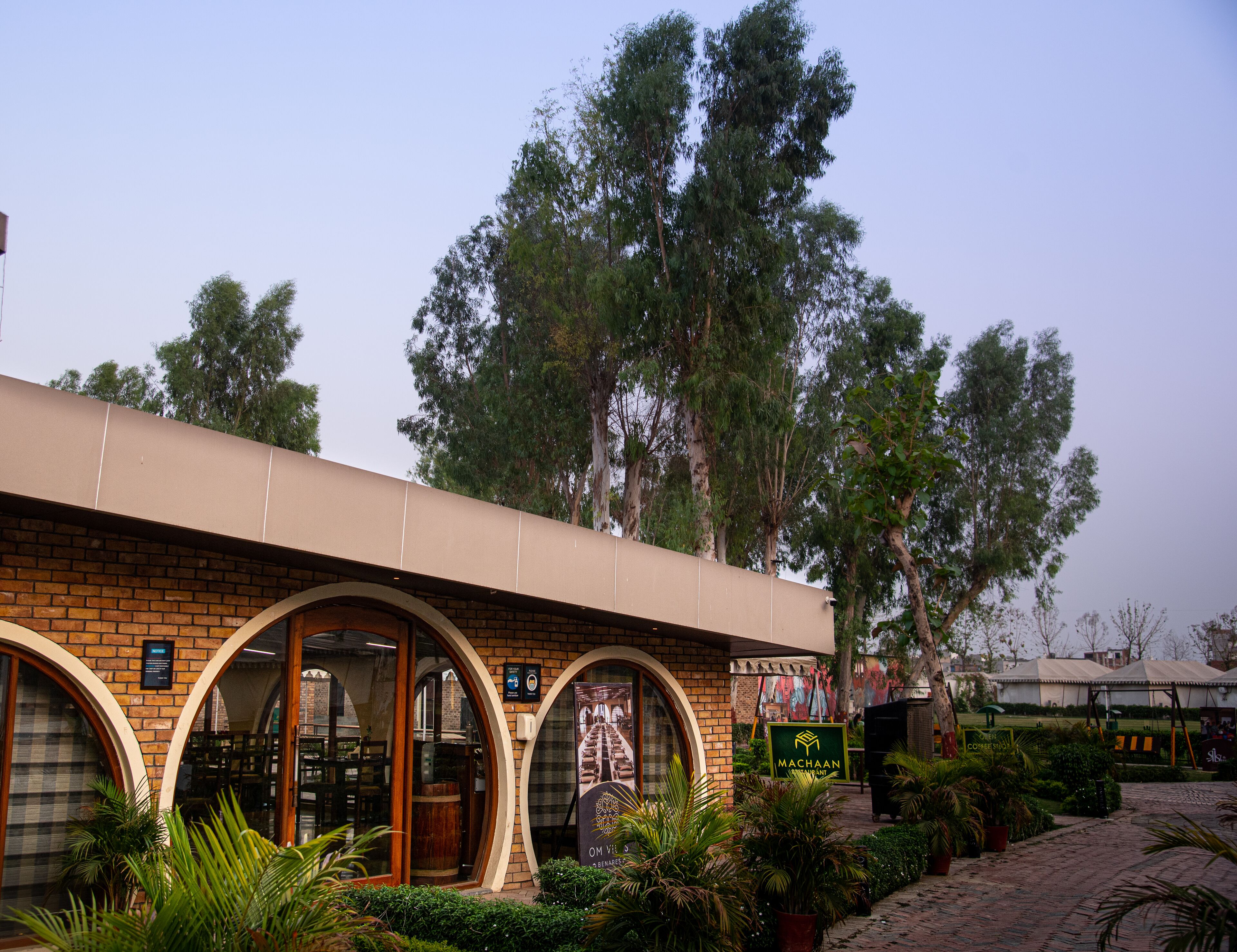 A building with arched windows and a brick facade, surrounded by greenery and trees.