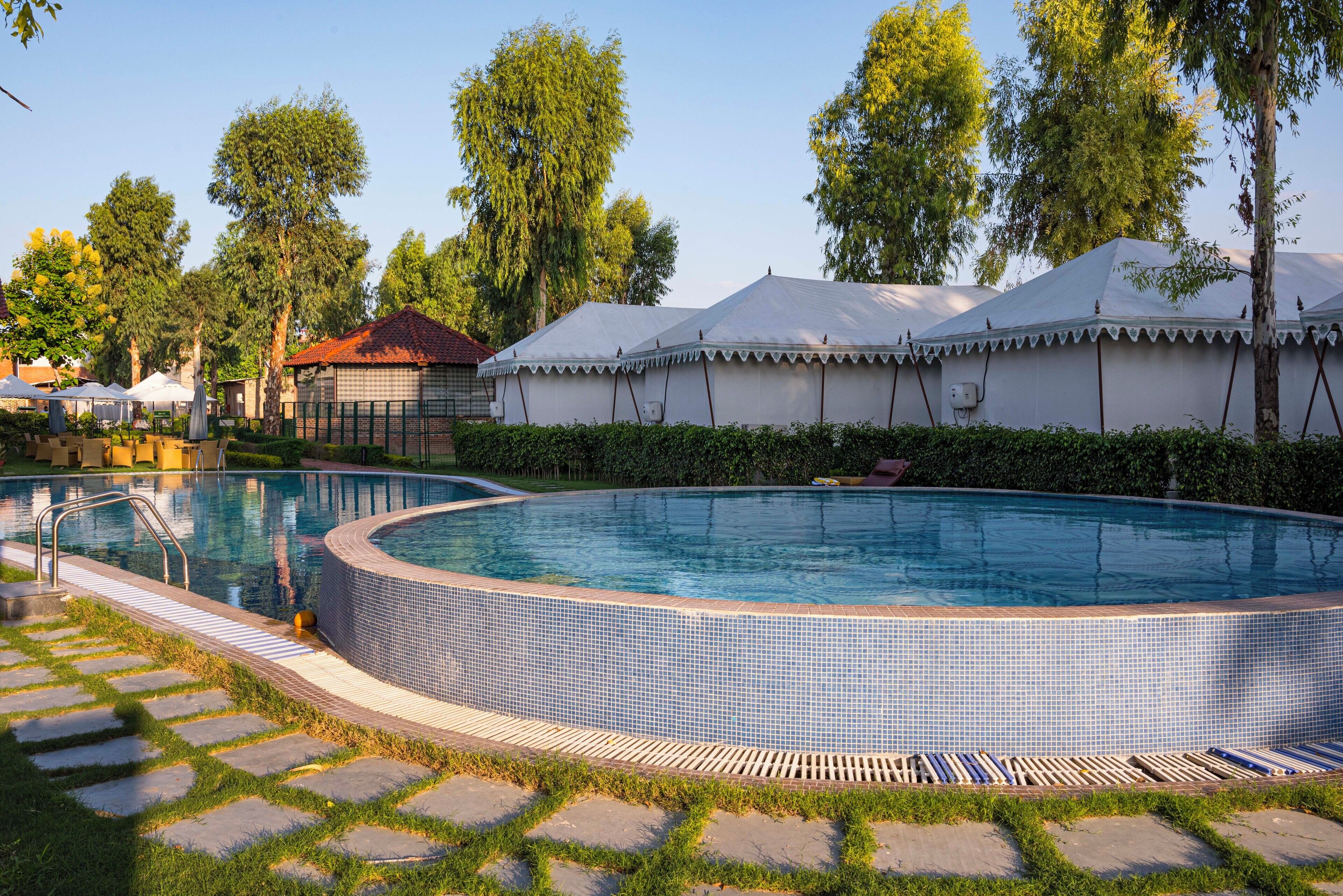 Een buitenzwembad, ligstoelen bij het zwembad