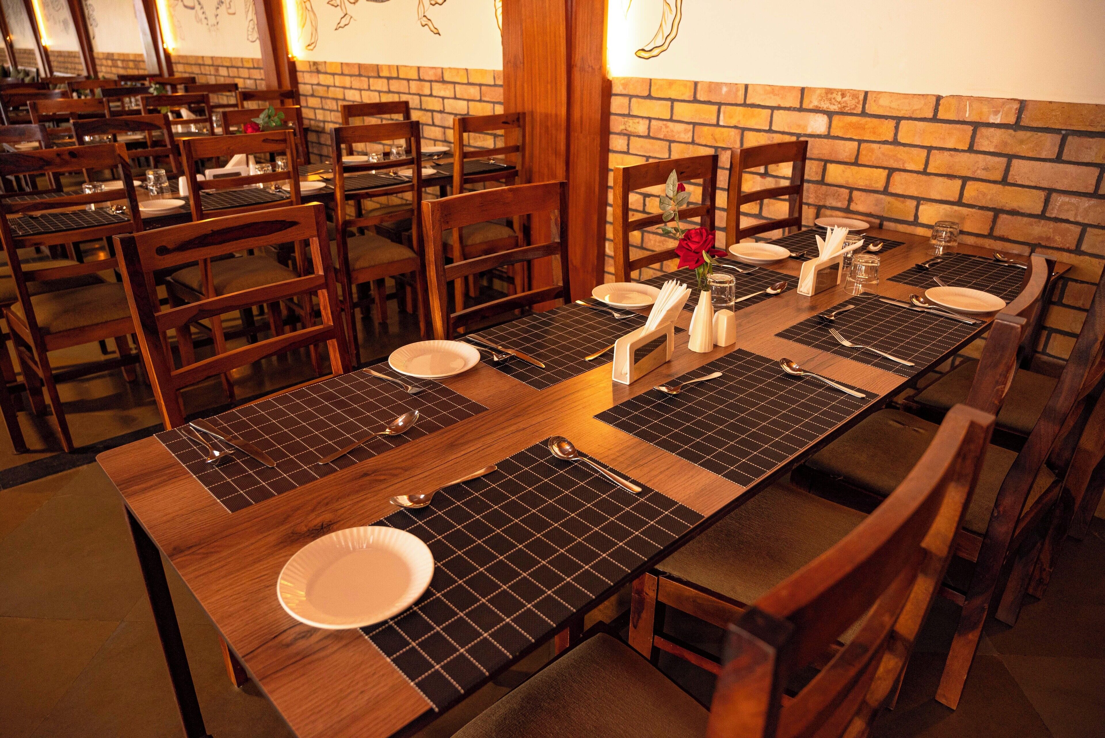 Un restaurant avec des tables et des chaises en bois, où les tables sont dressées avec des assiettes, des couverts et des serviettes.