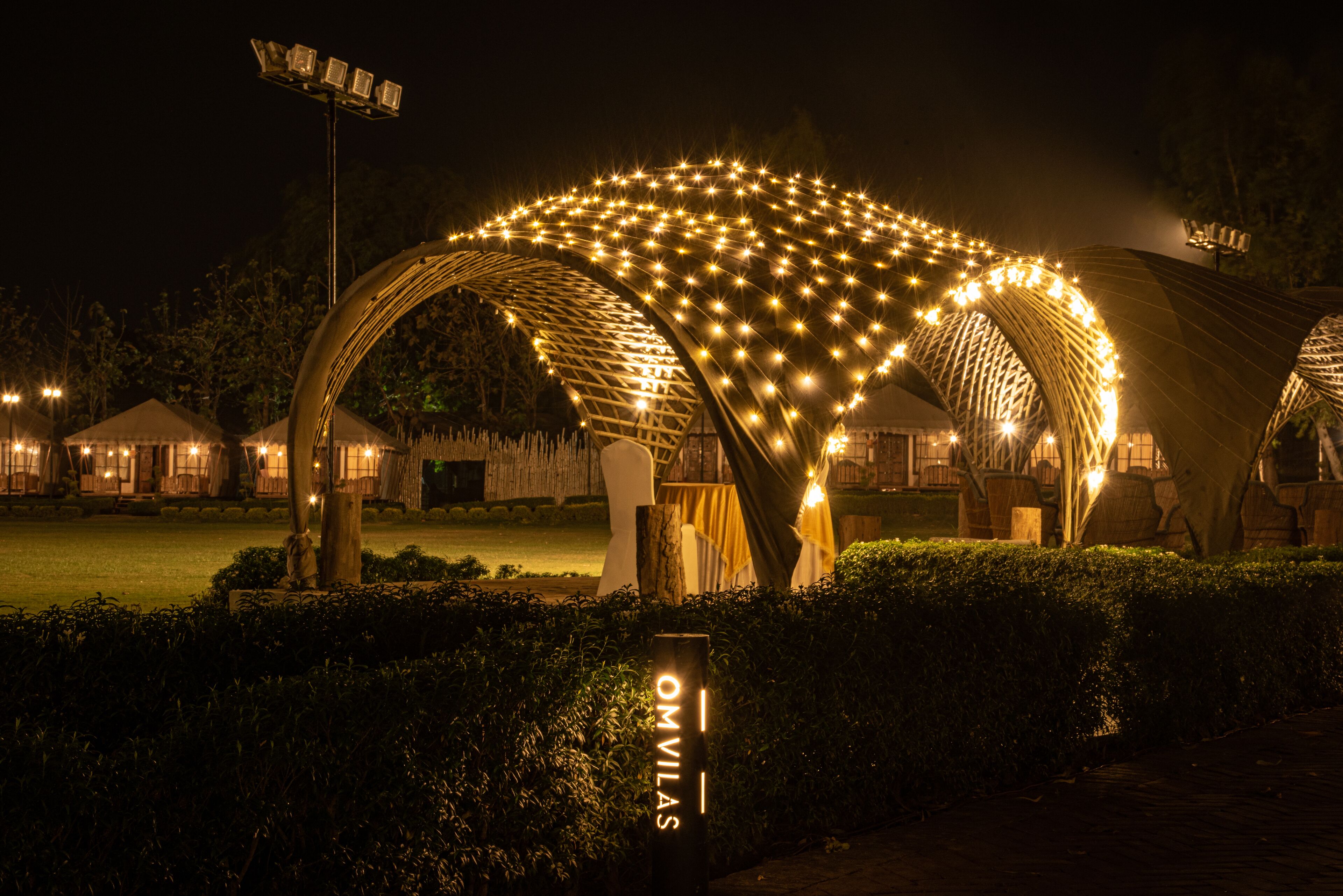 A night view of a hotel with illuminated arches and a sign reading "OMVILAS".
