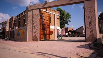 A building entrance with a large wooden gate, brick walls, and a mural on the side.