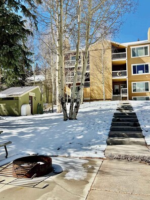 A snow-covered outdoor area with a concrete staircase leading to a building with multiple balconies.