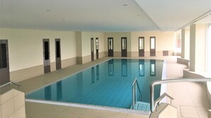 Une piscine intérieure à l’eau claire, avec des murs et un sol carrelés.